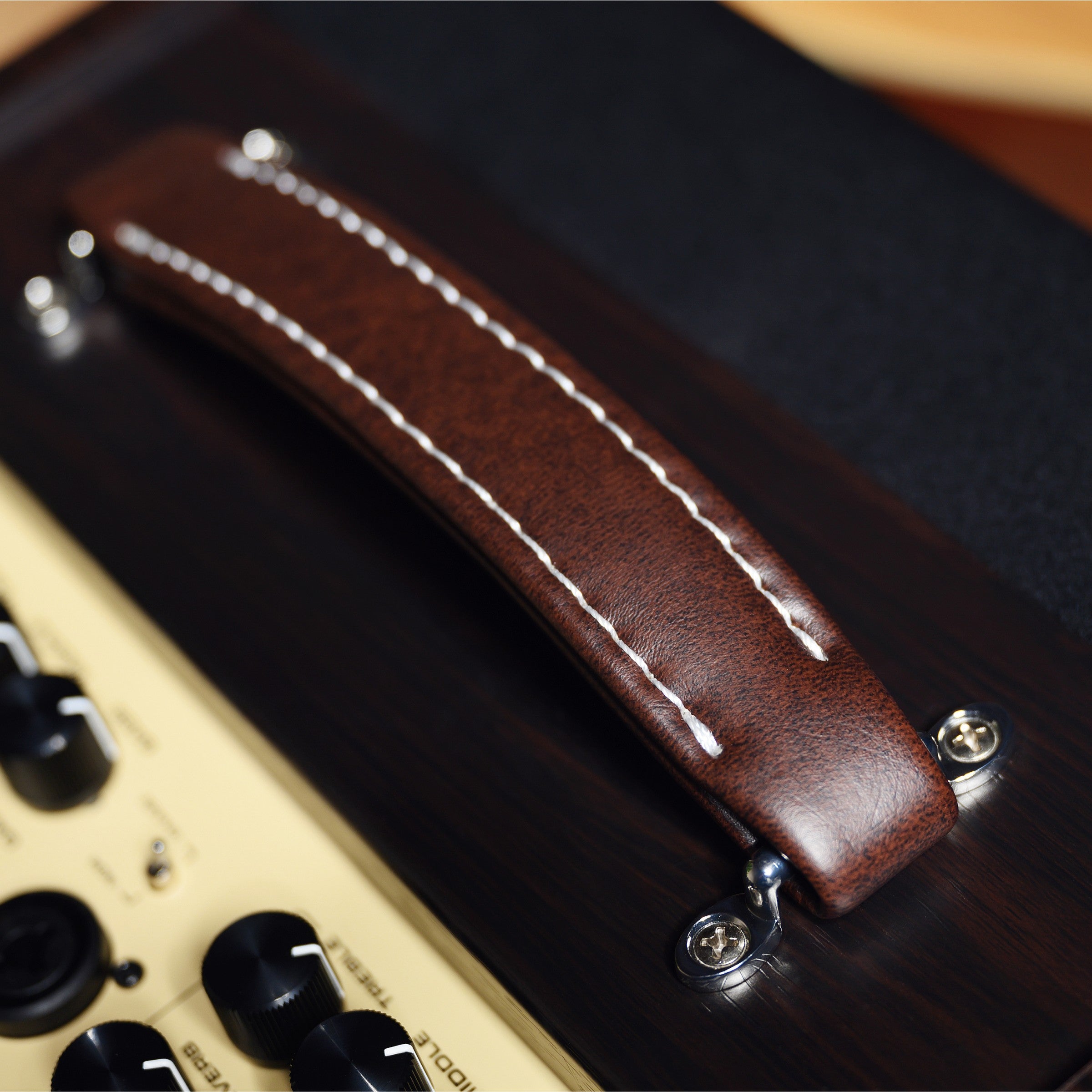 Close-up of a brown leather strap with metal hardware on a nux acoustic guitar amplifier.