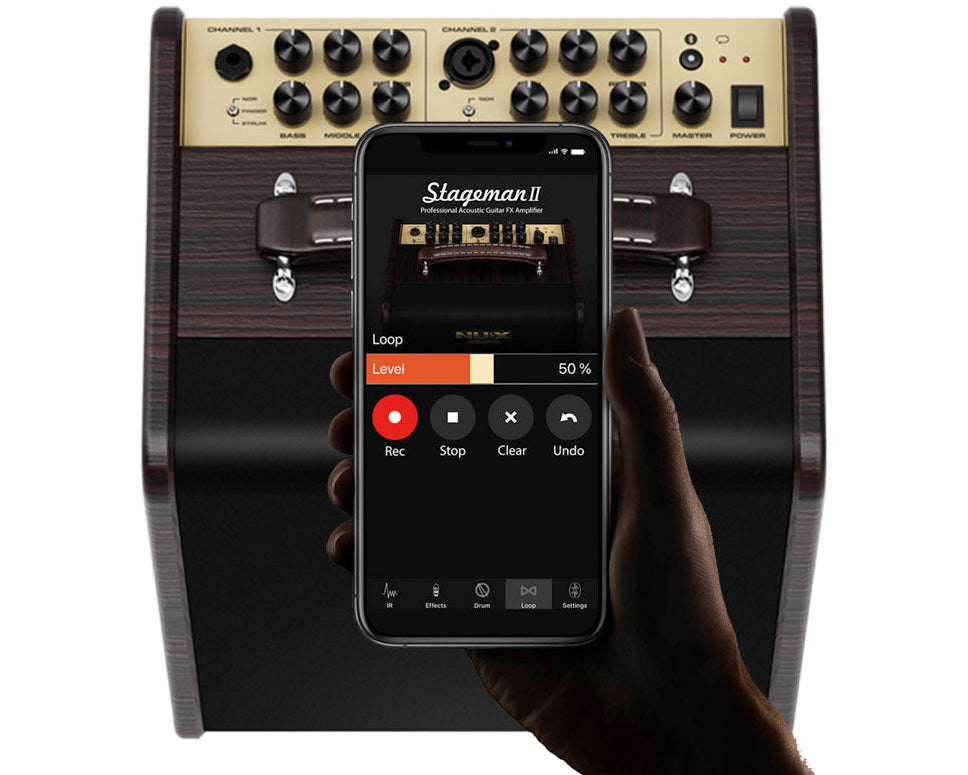 Hand holding a smartphone displaying an app interface in front of a Stageman II guitar effects processor.