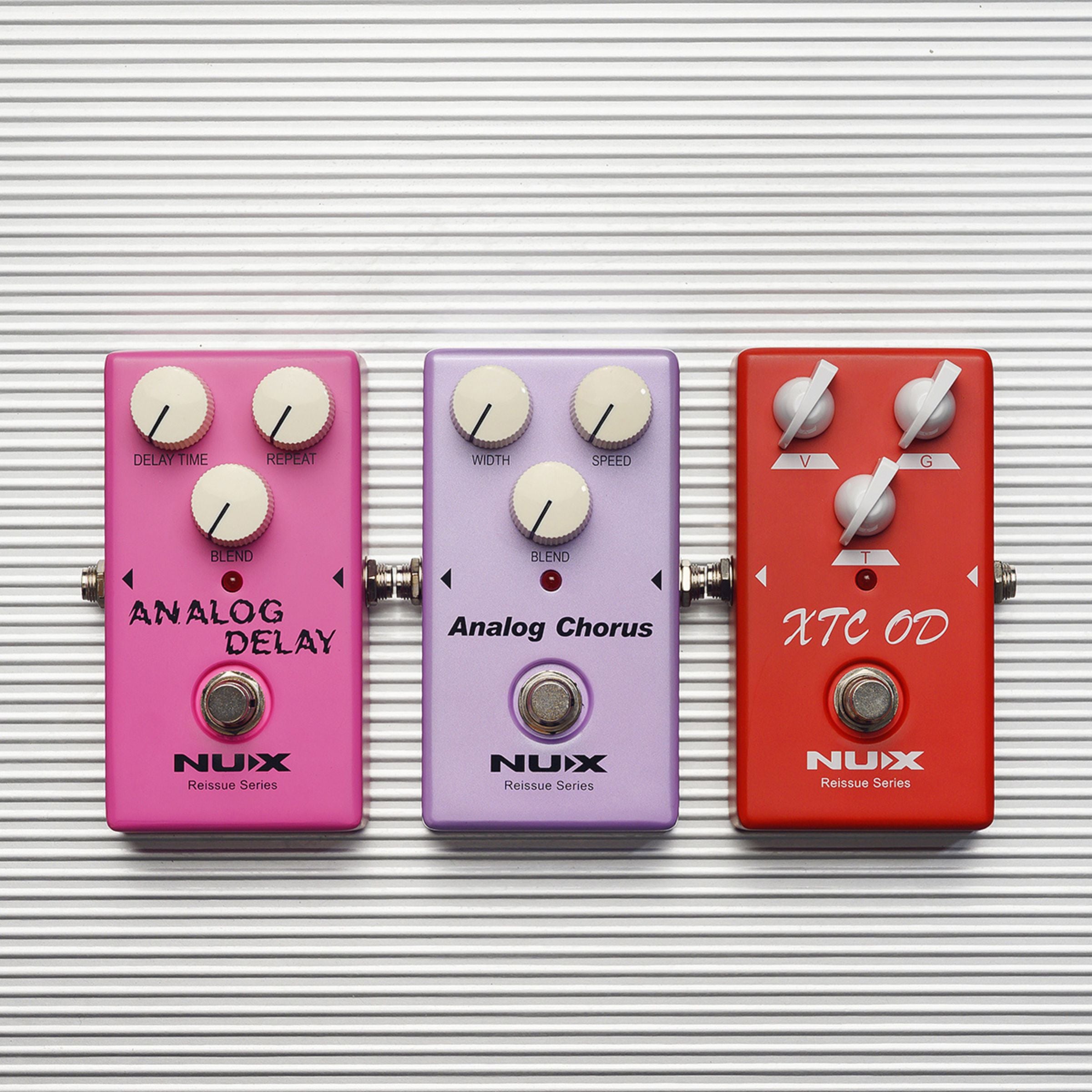 Three Nux guitar effect pedals on a striped background
