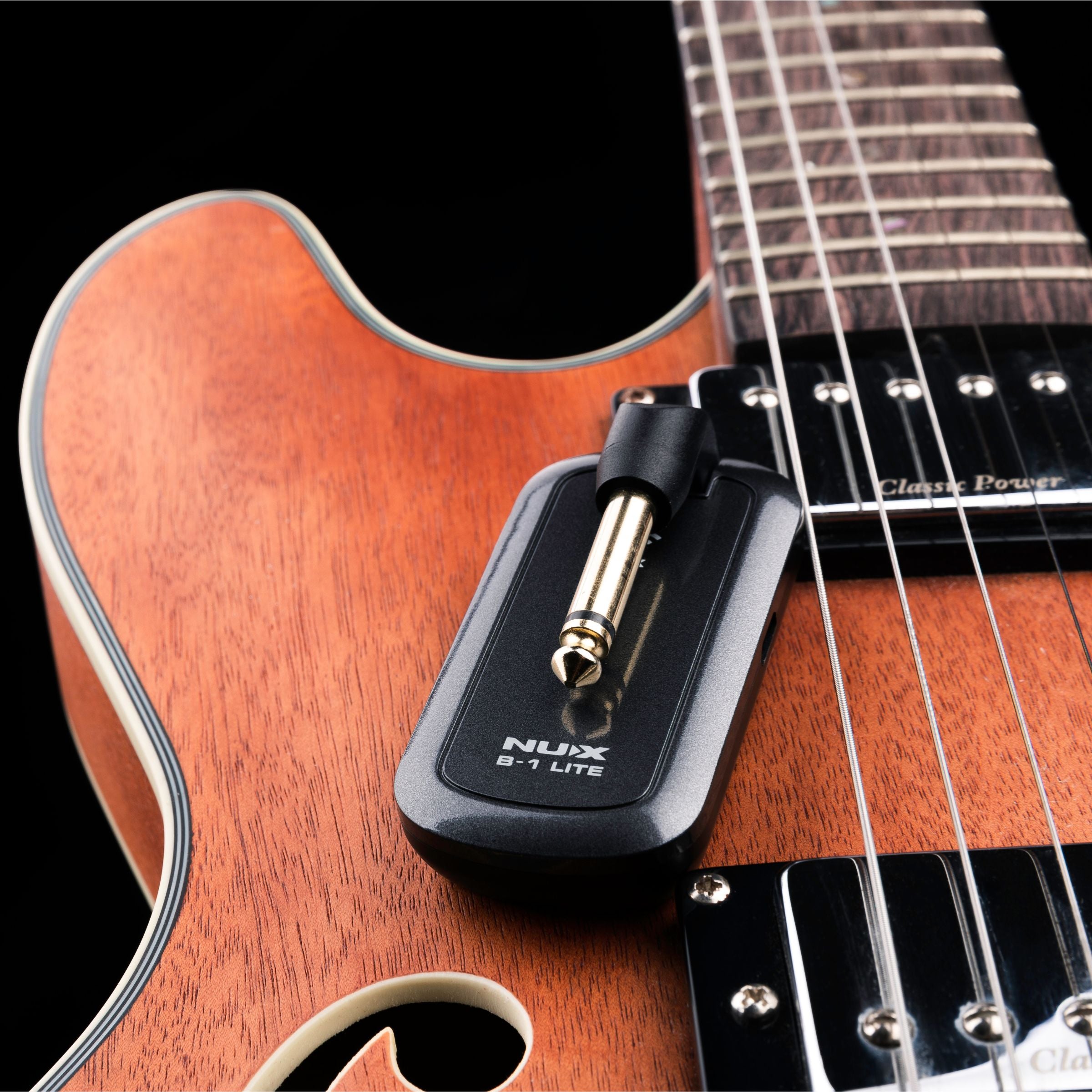 NUX B-1 LITE transmitter sitting on top of a guitar