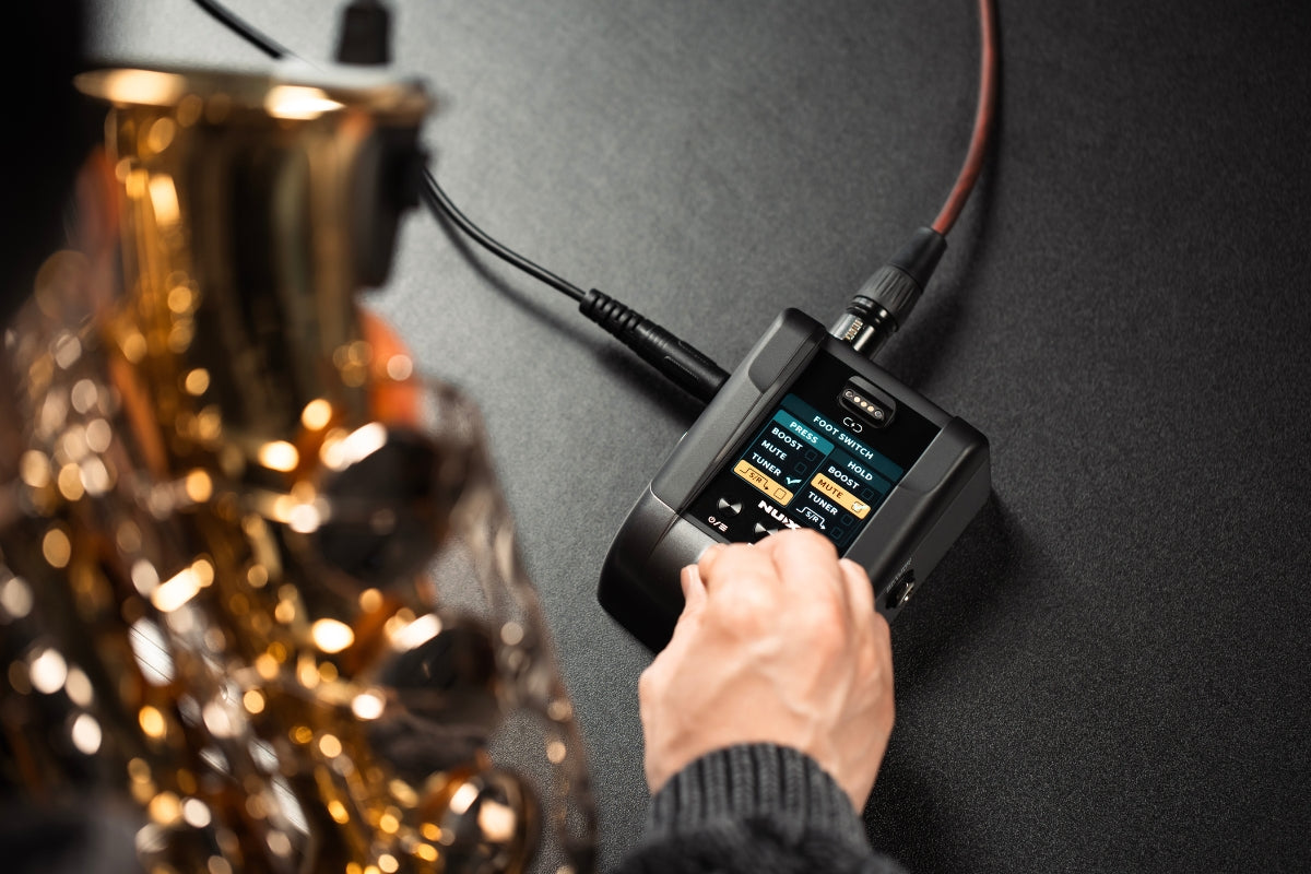Person adjusting NUX B-6 PRO pedalboard receiver foot switch option for their saxophone