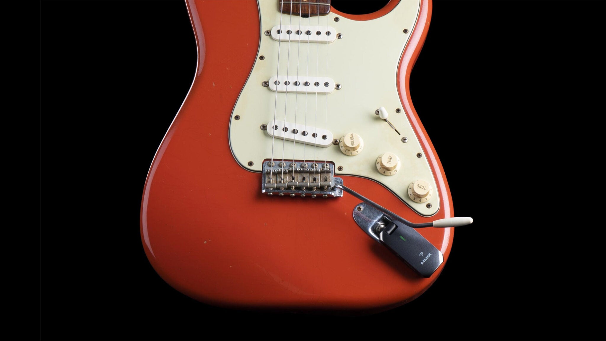 Red electric guitar with NUX C-5RC plugged in showing that the transmitter does not interfere with the design of the whammy bar