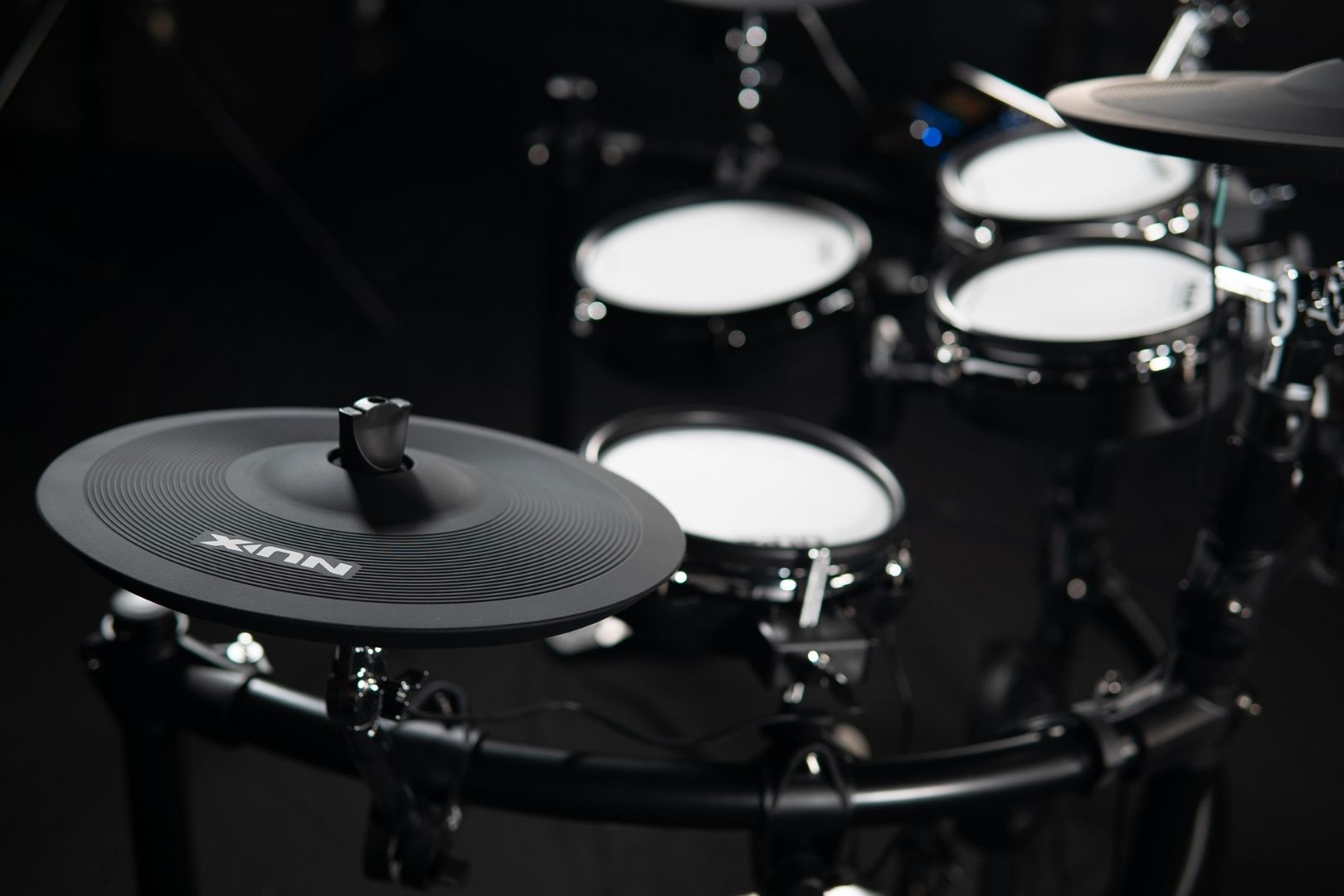 Close-up of a NUX drum set with a focus on the drums and stands.
