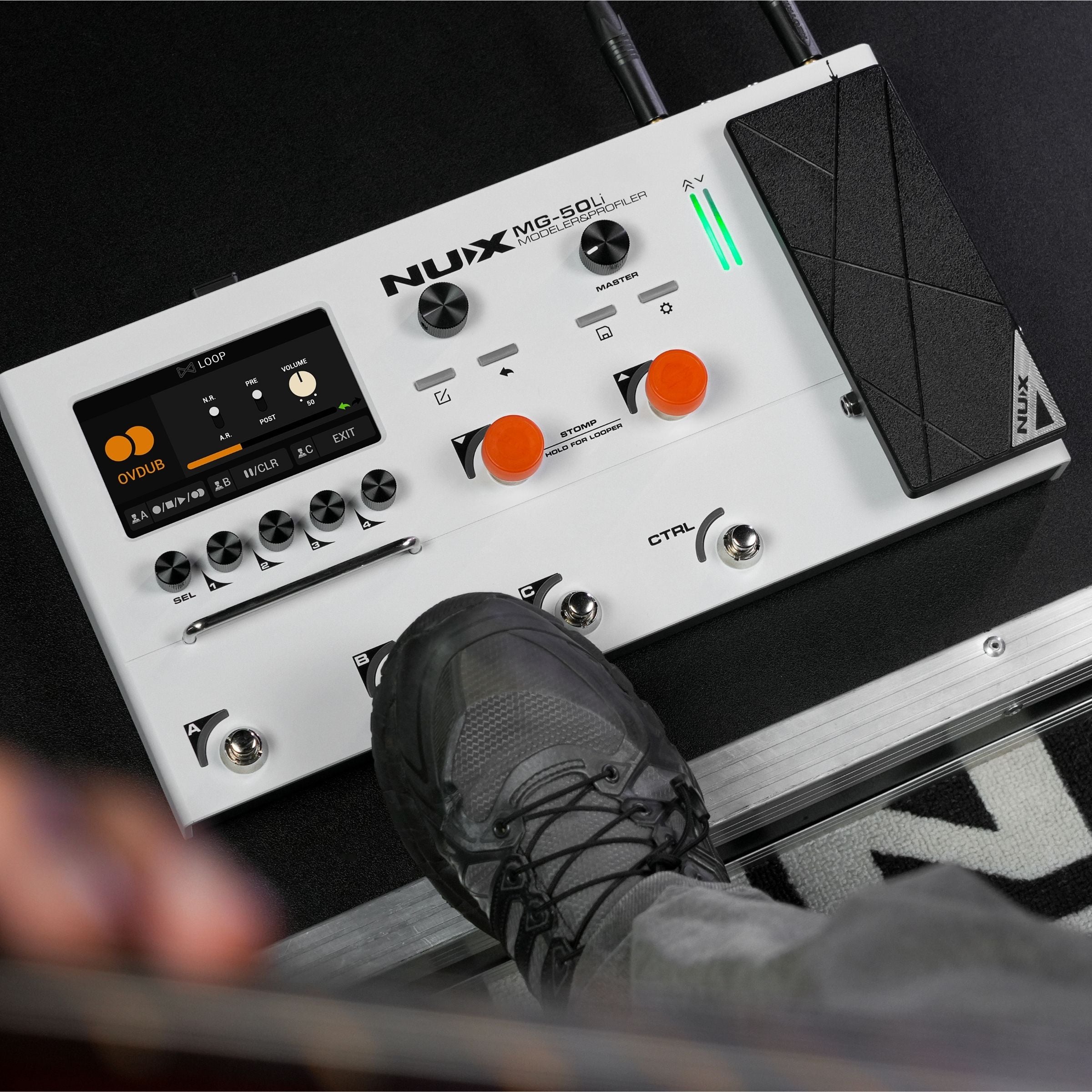 Nux MG-50LI guitar effects pedal on a dark surface with a person's foot stepping on it.