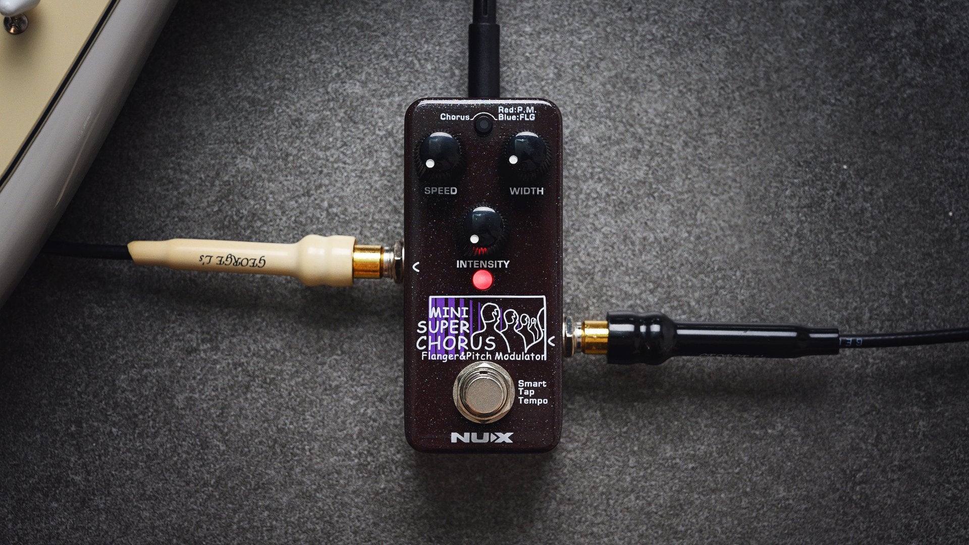 NUX Mini SCF effect guitar pedal on a dark background with input and output jacks plugged in.