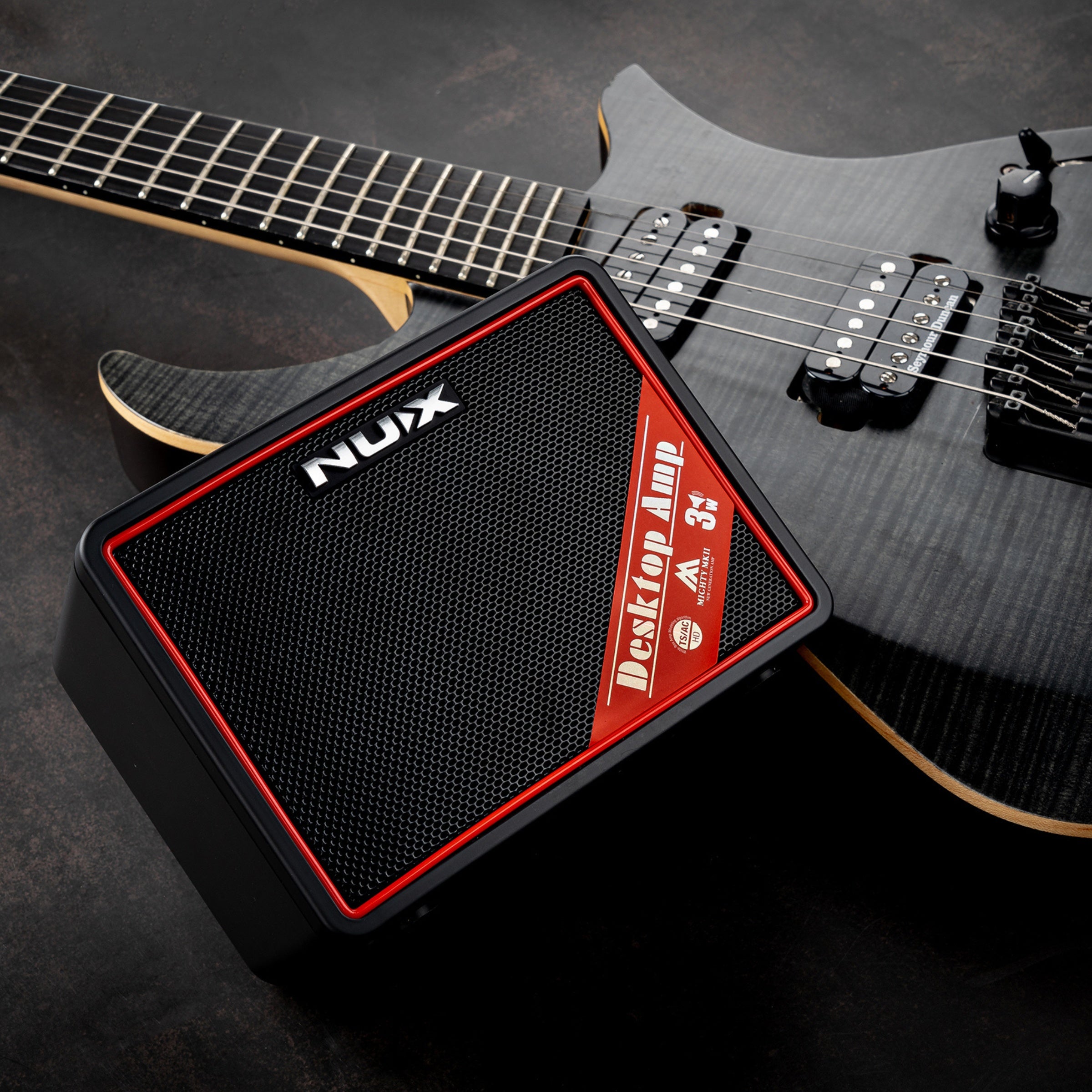 NUX Portable amp mighty lite next to a dark gray electric guitar