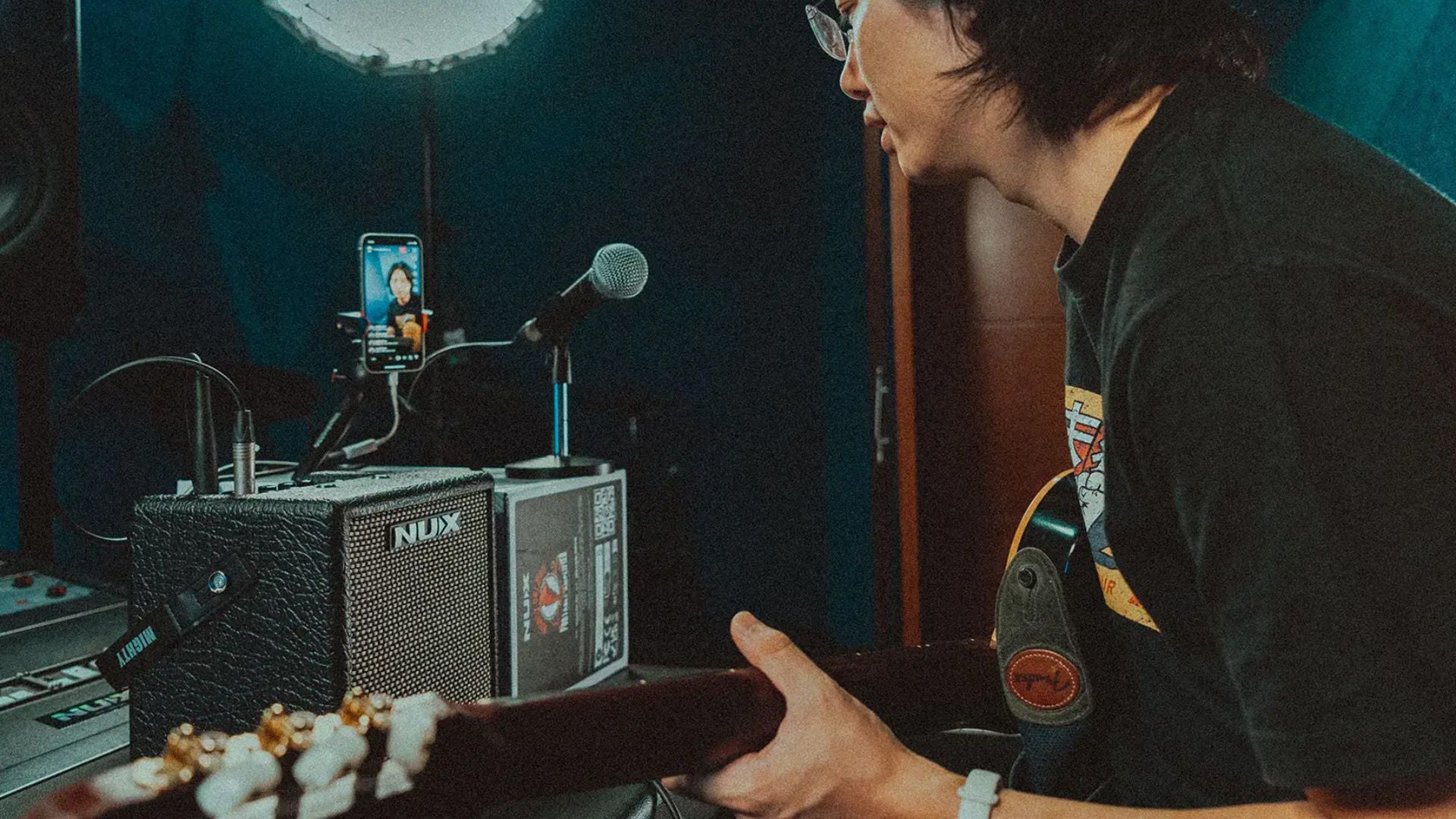 person playing guitar while live streaming and using NUX amp