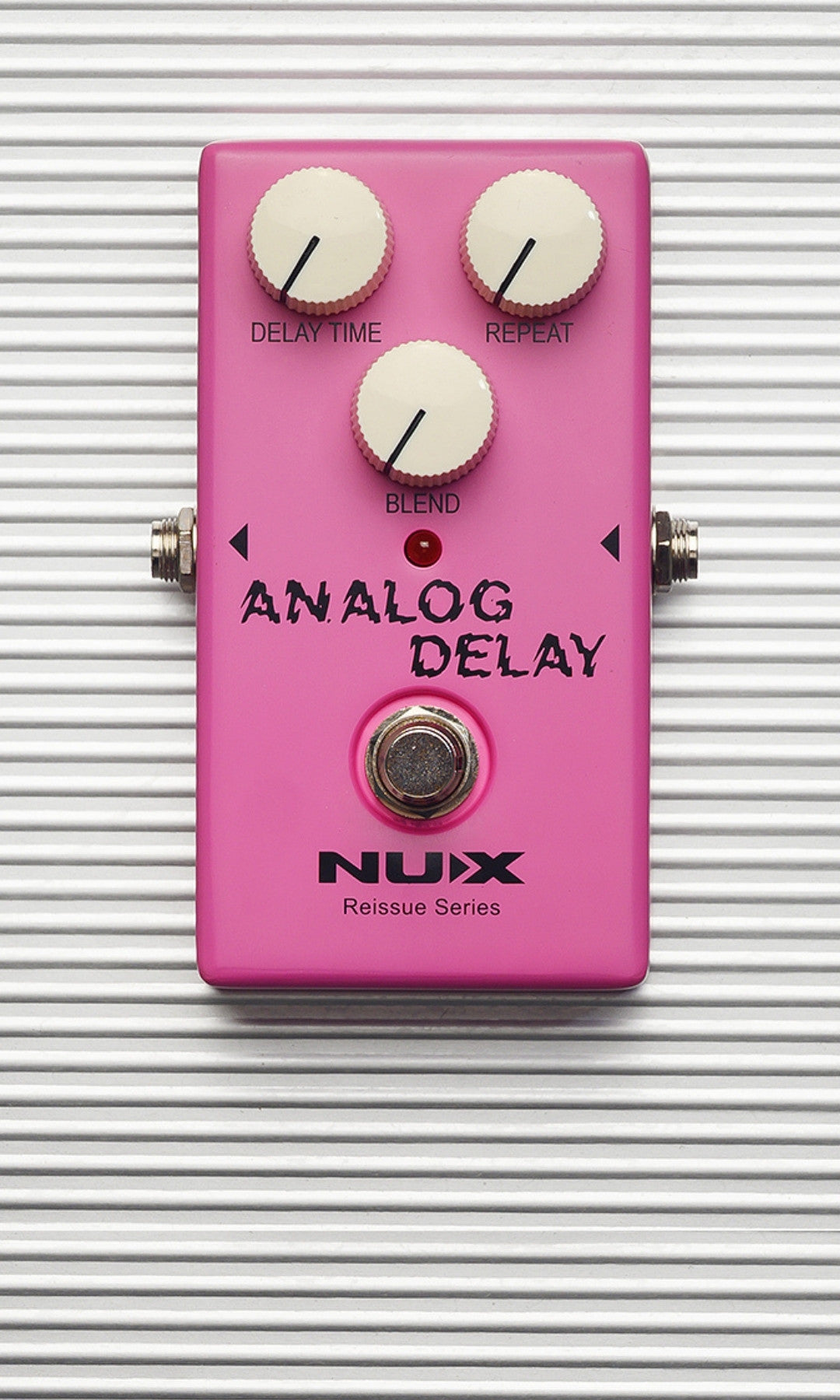 Pink Nux Analog Delay guitar effects pedal on a striped background