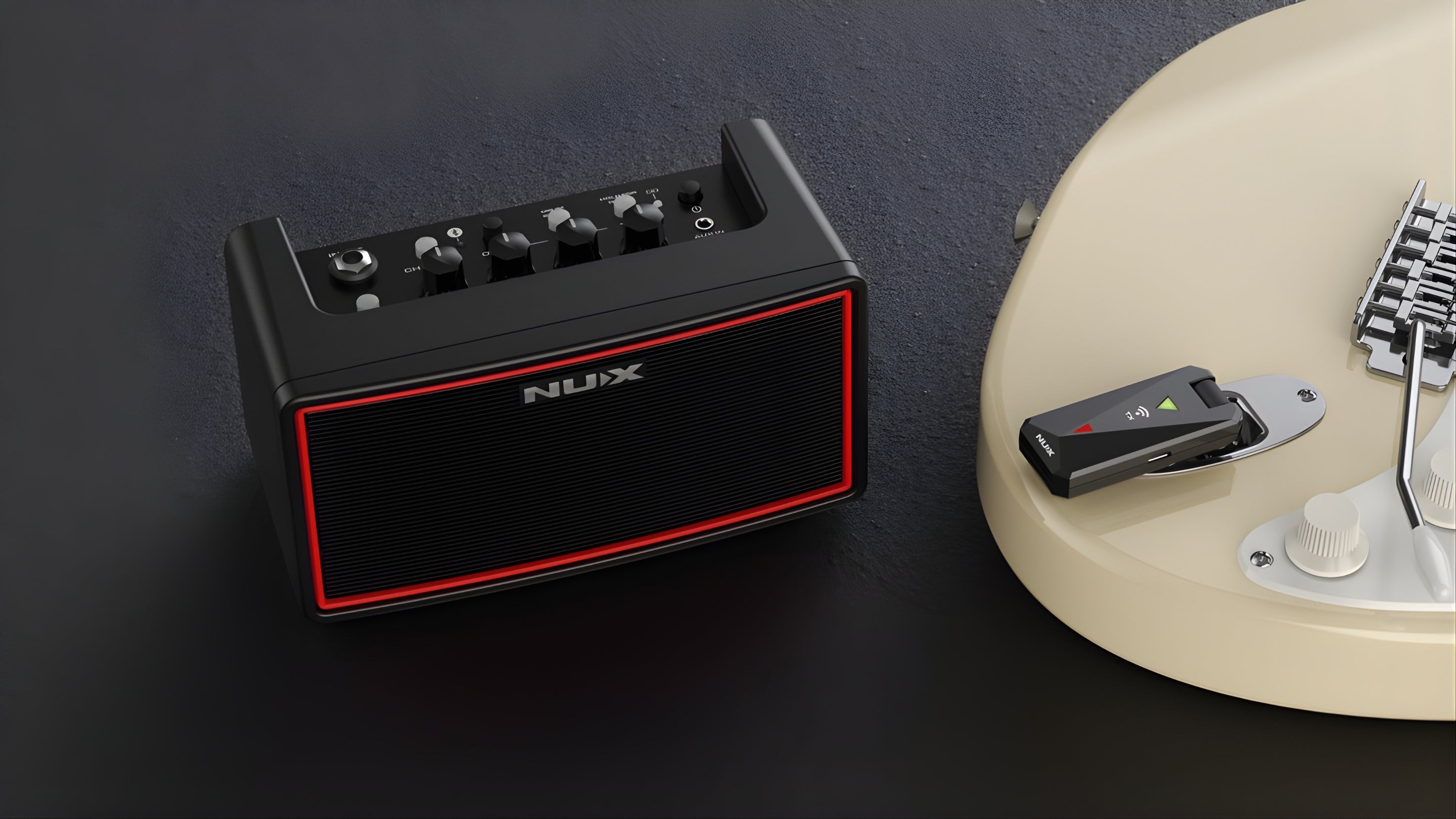 NUX small mighty air amp next to an electric guitar with a transmitter plugged in on a dark surface background