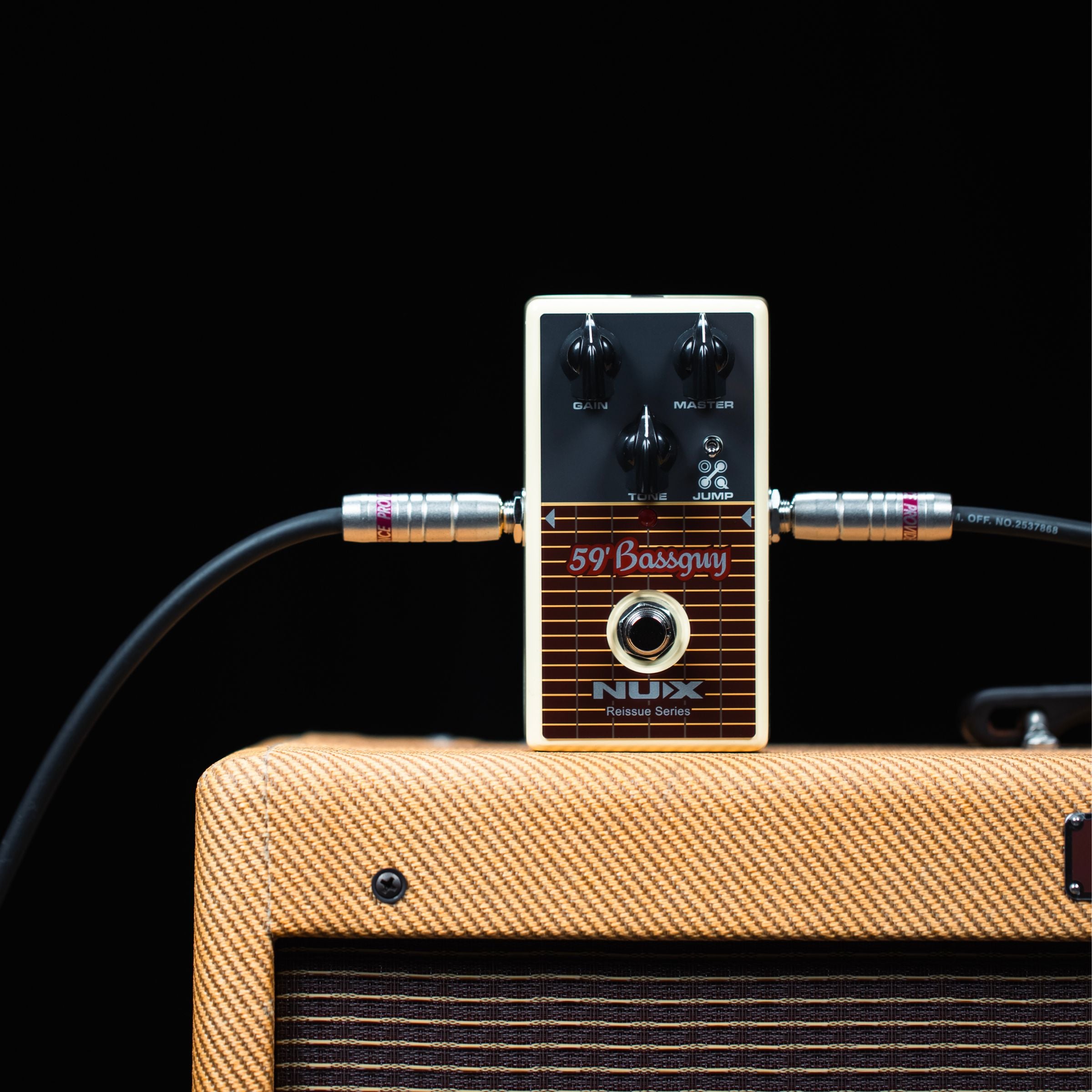 NUX 59 bassguy Guitar effects pedal with cables connected to a amplifier on a black background