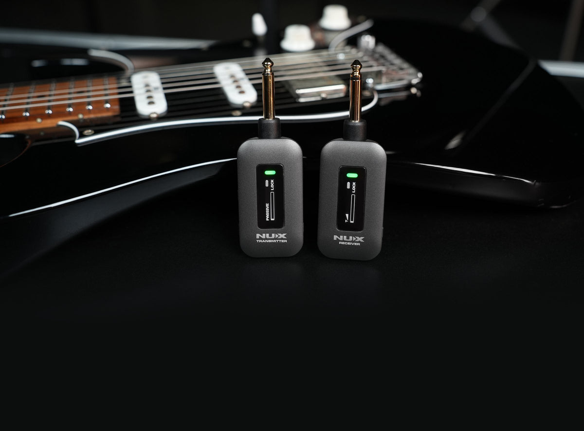 NUX C-58RC wireless transmitter and receiver standing upright on a black electric guitar