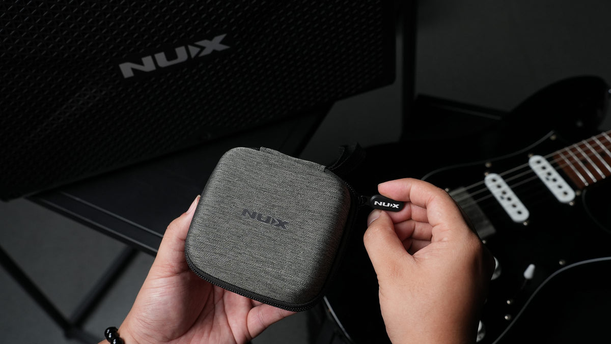 Compact NUX C-58RC charging case held next to a guitar