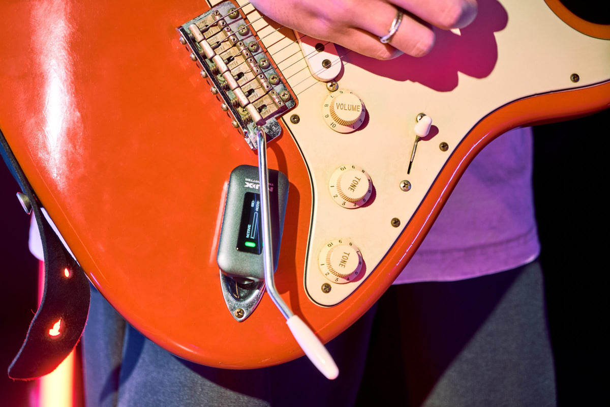 NUX C-58RC transmitter sitting clear of the tremolo on an orange electric guitar