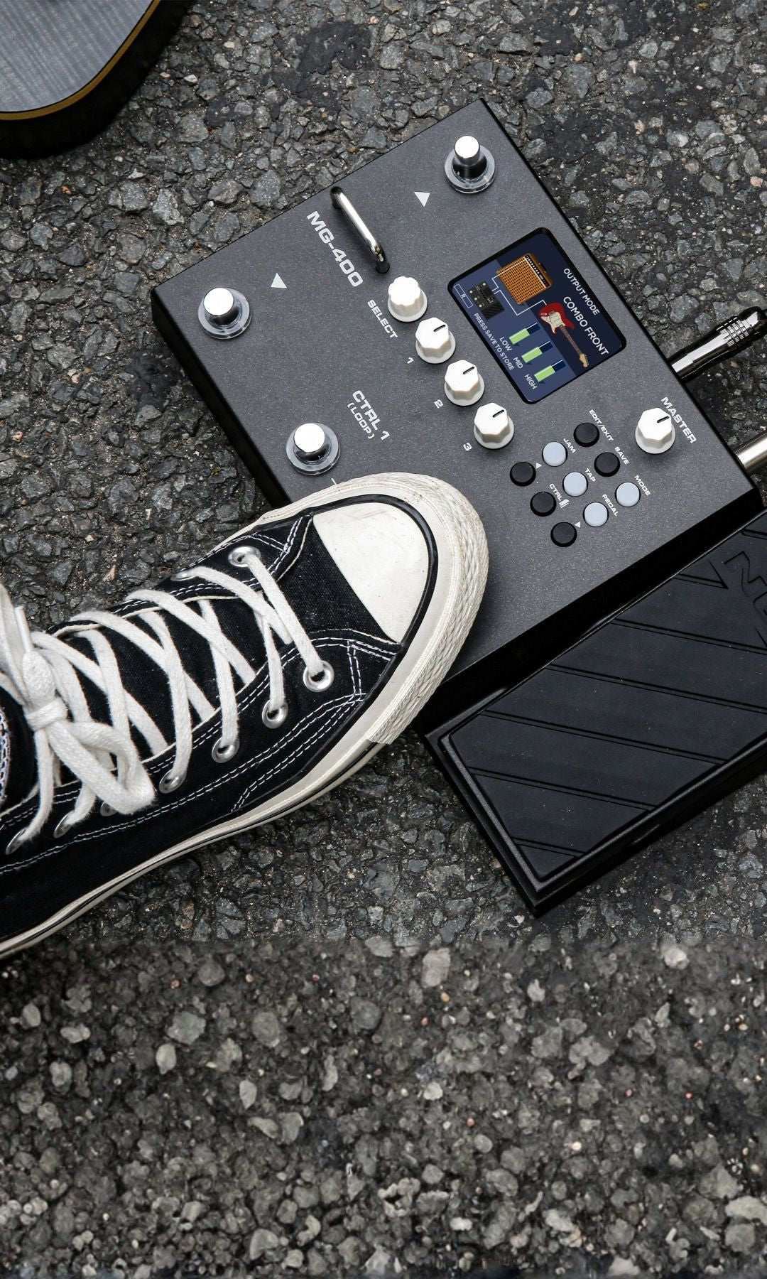 Black and white sneaker stepping on a NU-X MG-400 guitar effects modeler pedal on a concrete surface