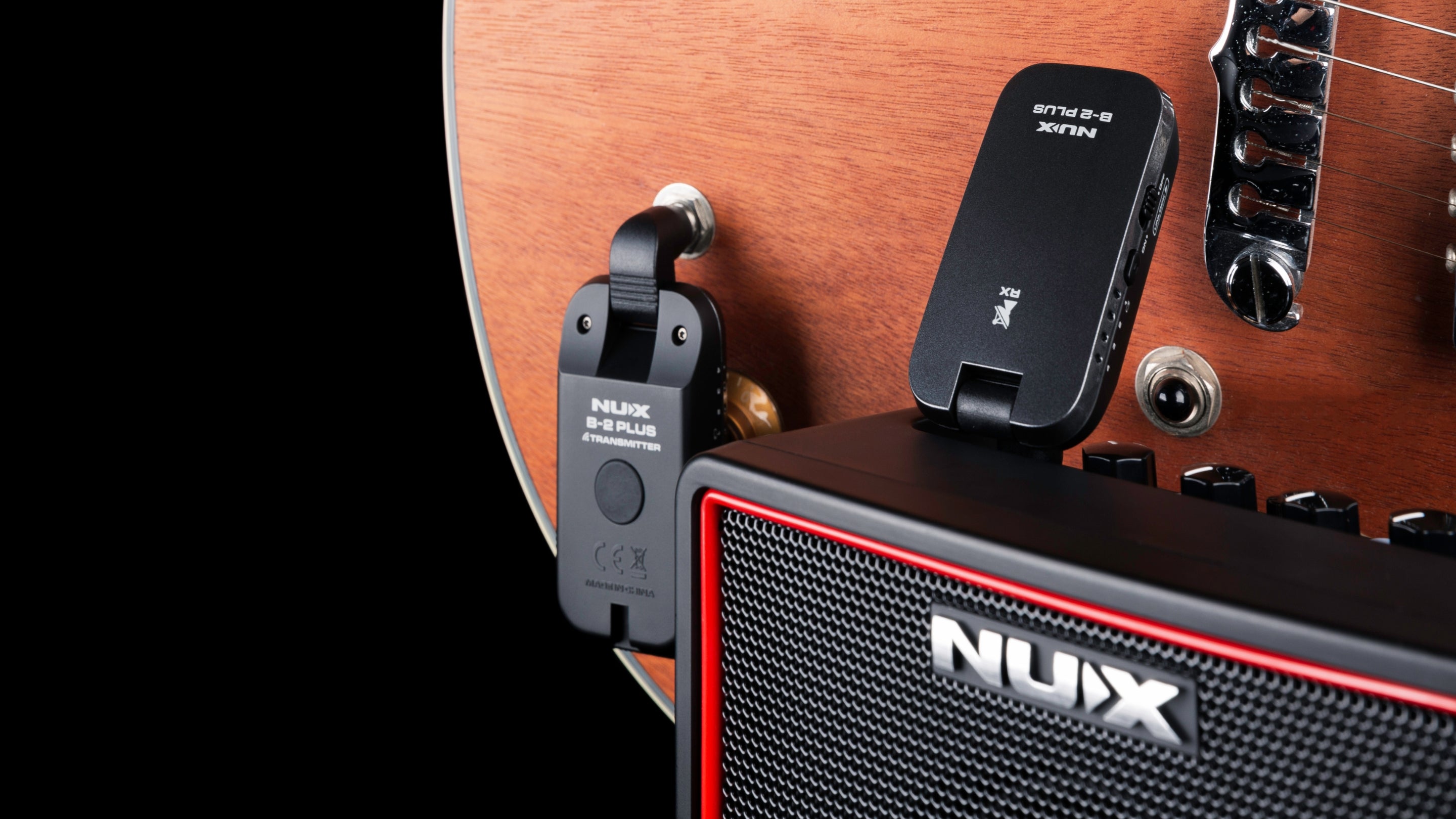 NUX wireless guitar transmitter plugged into an acoustic guitar with the receiver plugged in to a NUX amplifier.