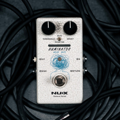 Nux Huminator noise gate pedal surrounded by cables on a dark background