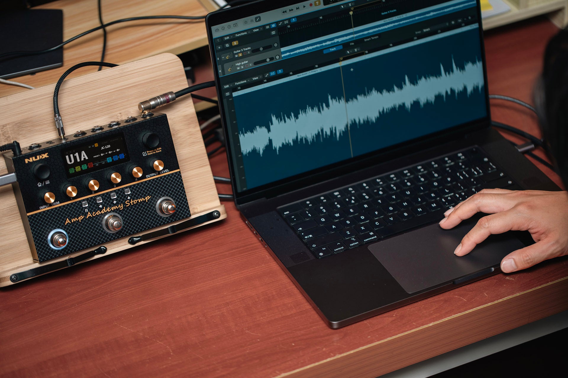 Laptop with audio software on a desk next to NUX amp academy stomp