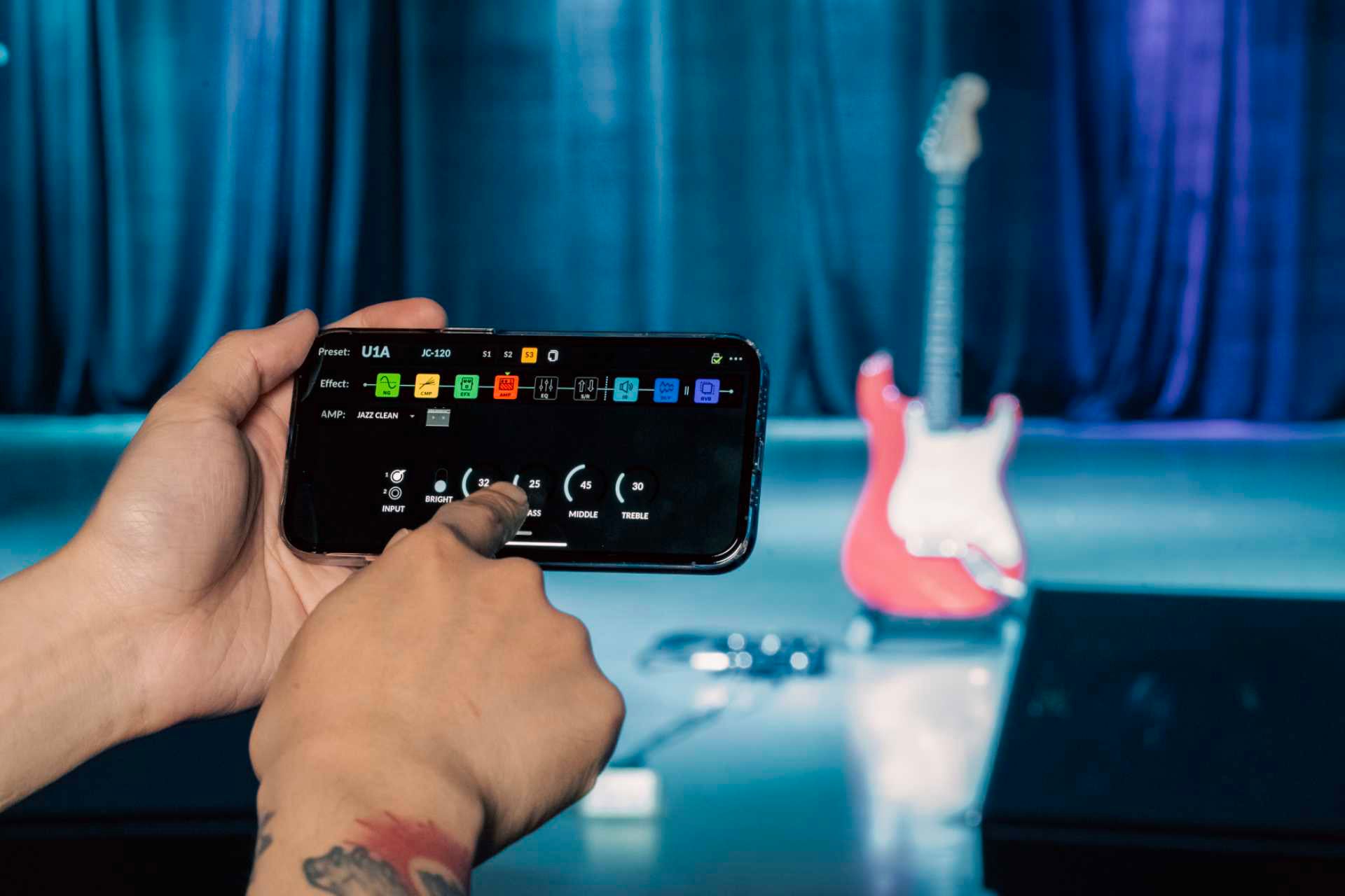 Person using a smartphone app on stage with musical equipment in the background
