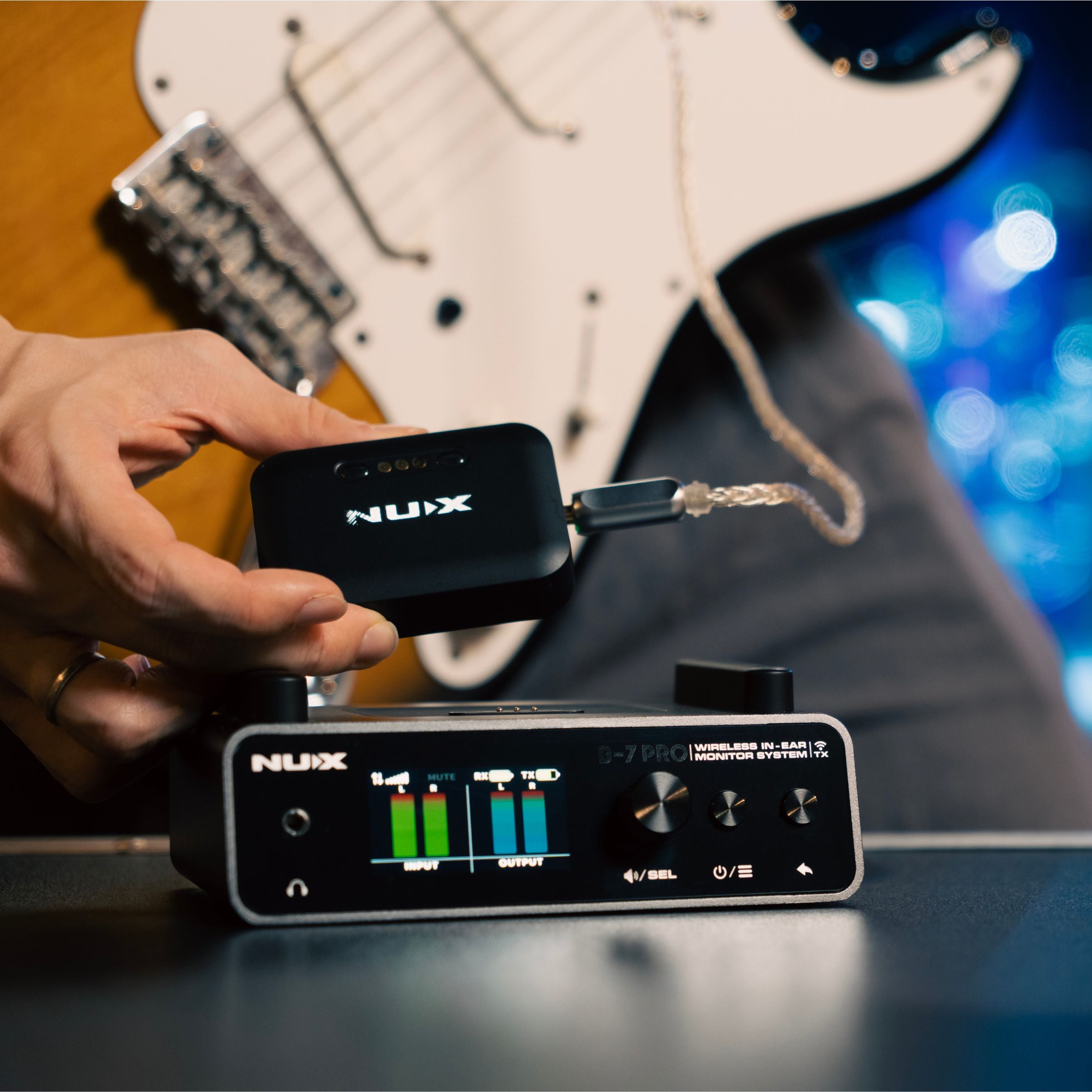 Guitarist NUX B-7 PRO wireless in-ear monitor receiver with headphones plugged in next to the transmitter showing the output volume at max level.