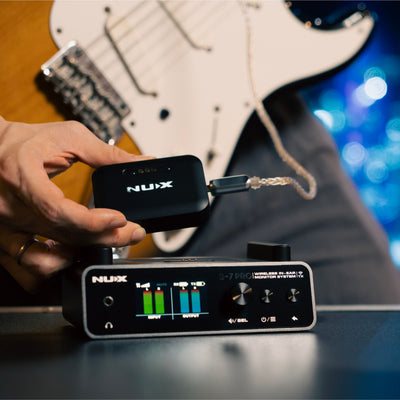 Guitarist NUX B-7 PRO wireless in-ear monitor receiver with headphones plugged in next to the transmitter showing the output volume at max level.