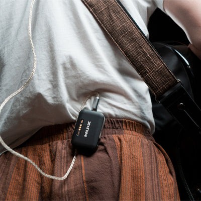 Guitarist wearing NUX B-7 PRO receiver clipped onto back pants.
