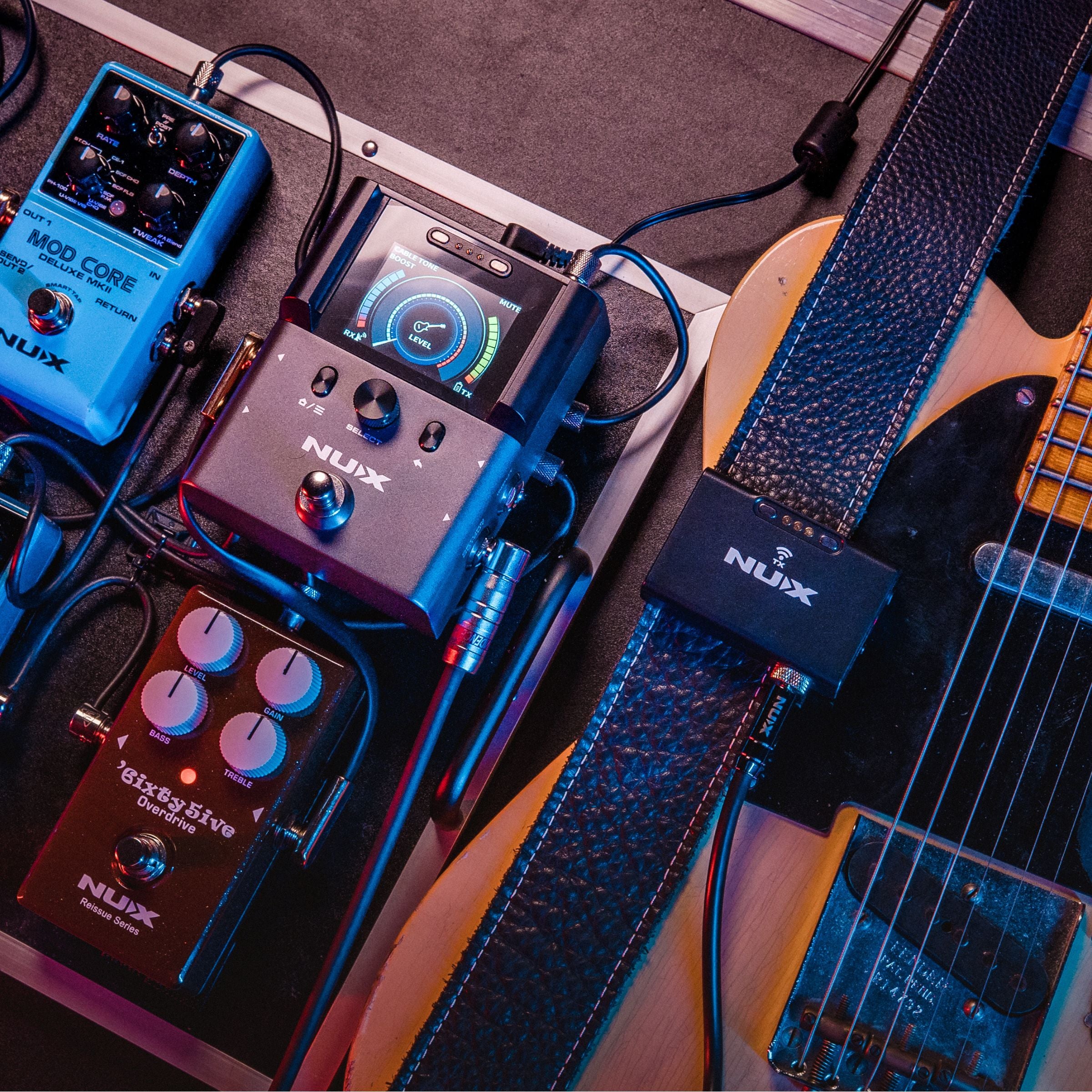 Guitar with effects pedals connected to NUX B-8 pedalboard receiver and the transmitter clipped on the straps.