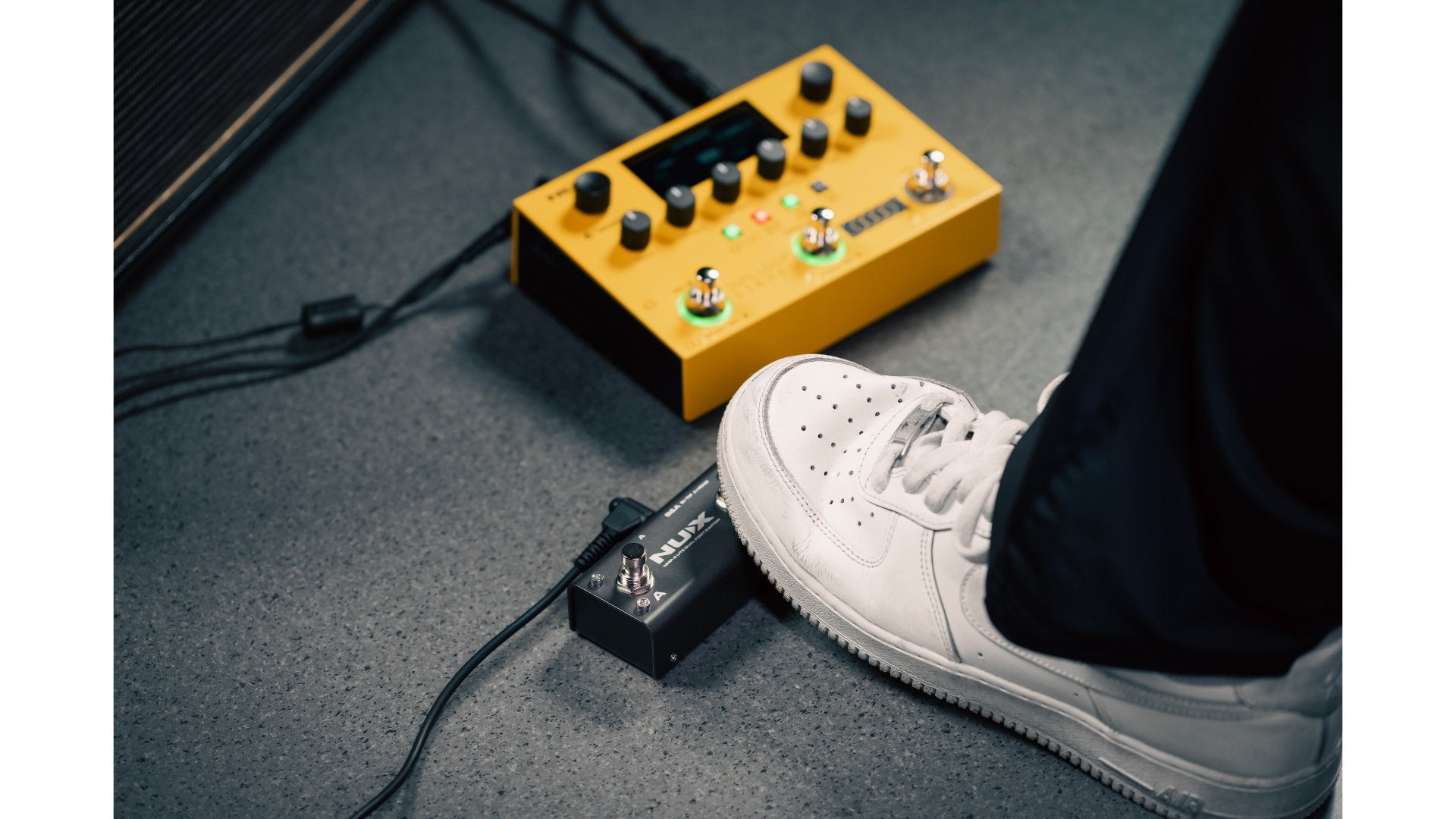 person stepping on one of the button of the included footswitch for NUX dual loop stereo