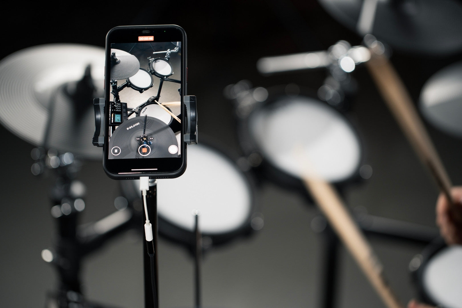 A smartphone connected to NUX DM-310H recording a drum session.