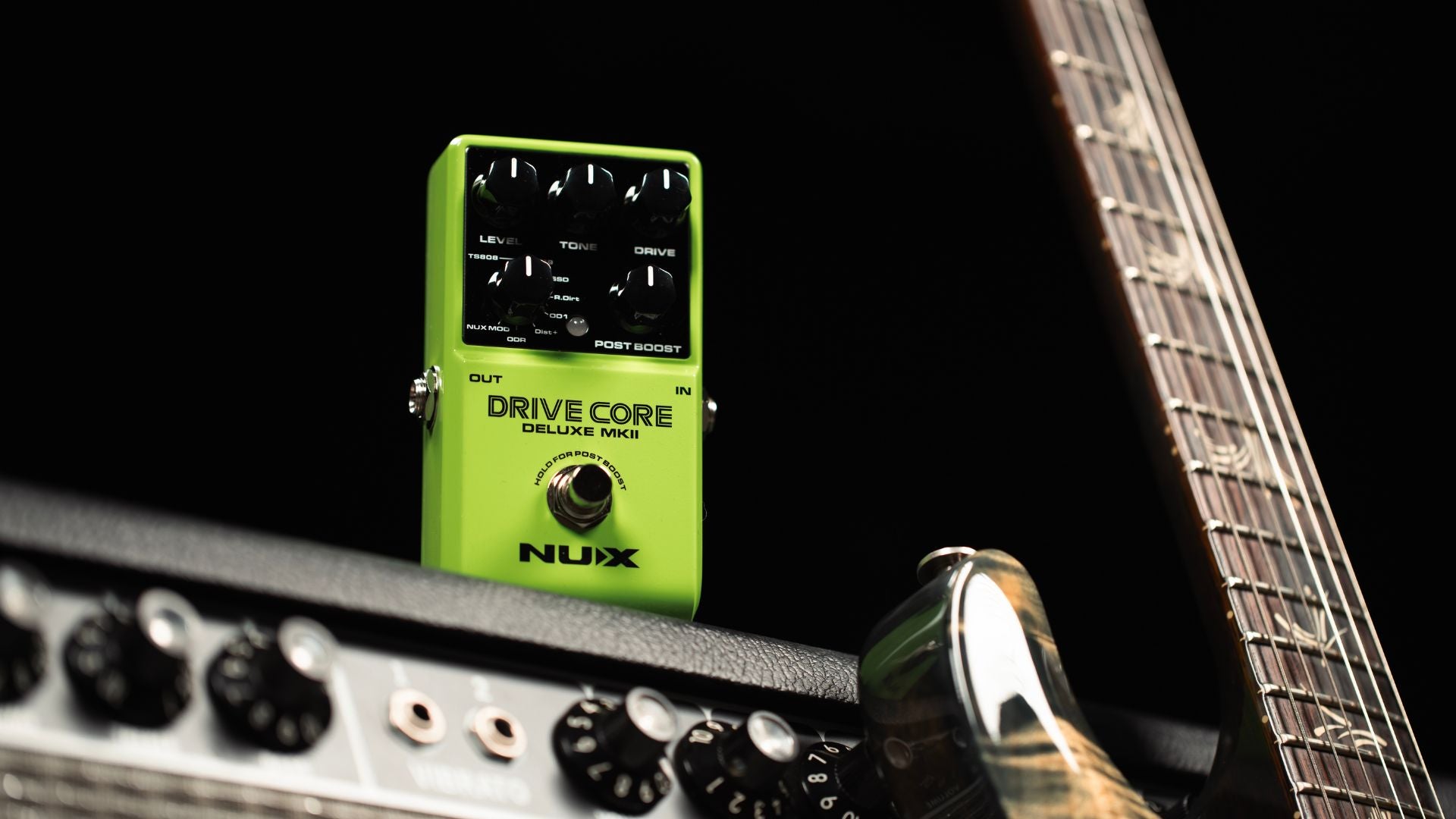 Green Nux guitar effects pedal on a guitar with a black background