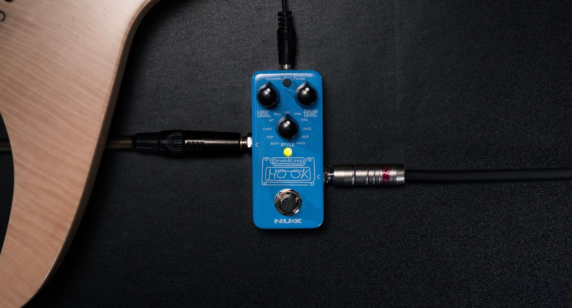 Blue NUX HOOK Drum & LOOp guitar effects pedal with cables attached on a dark background