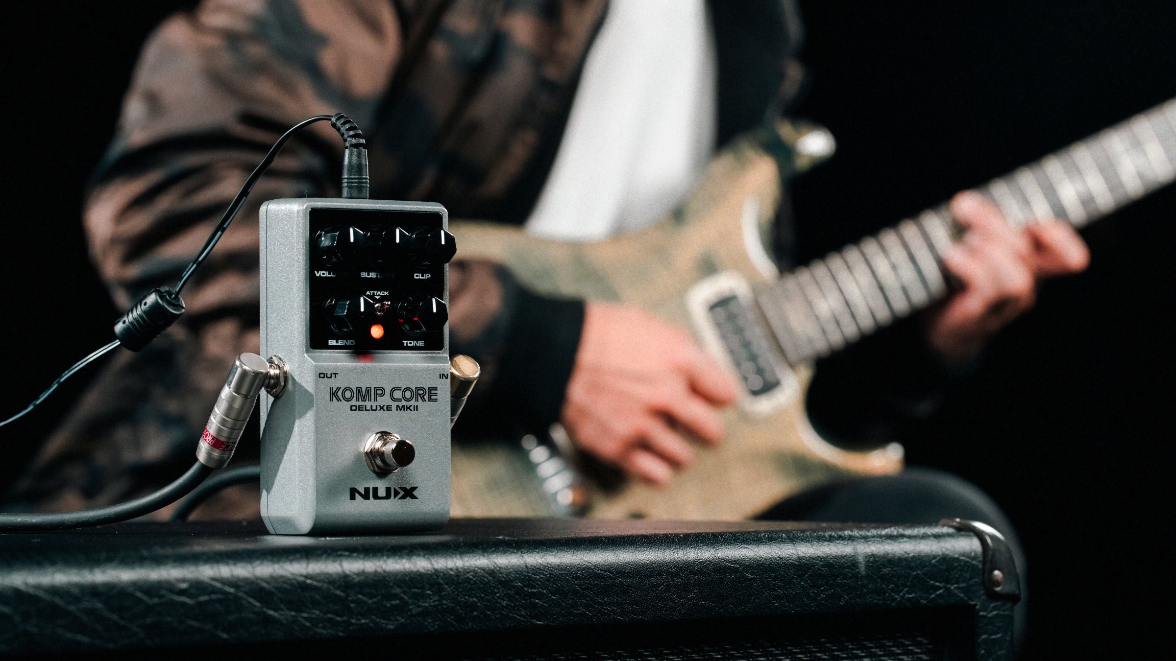 NUX Komp Core with a guitarist in the background