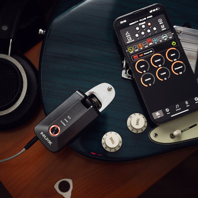 Guitar with a phone with digital effects controller app on and NUX Mighty Plug Pro plugged in on a wooden surface