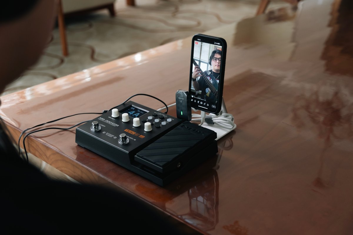 Person livestreaming guitar performance using NUX MG-300 MKII modeller interface