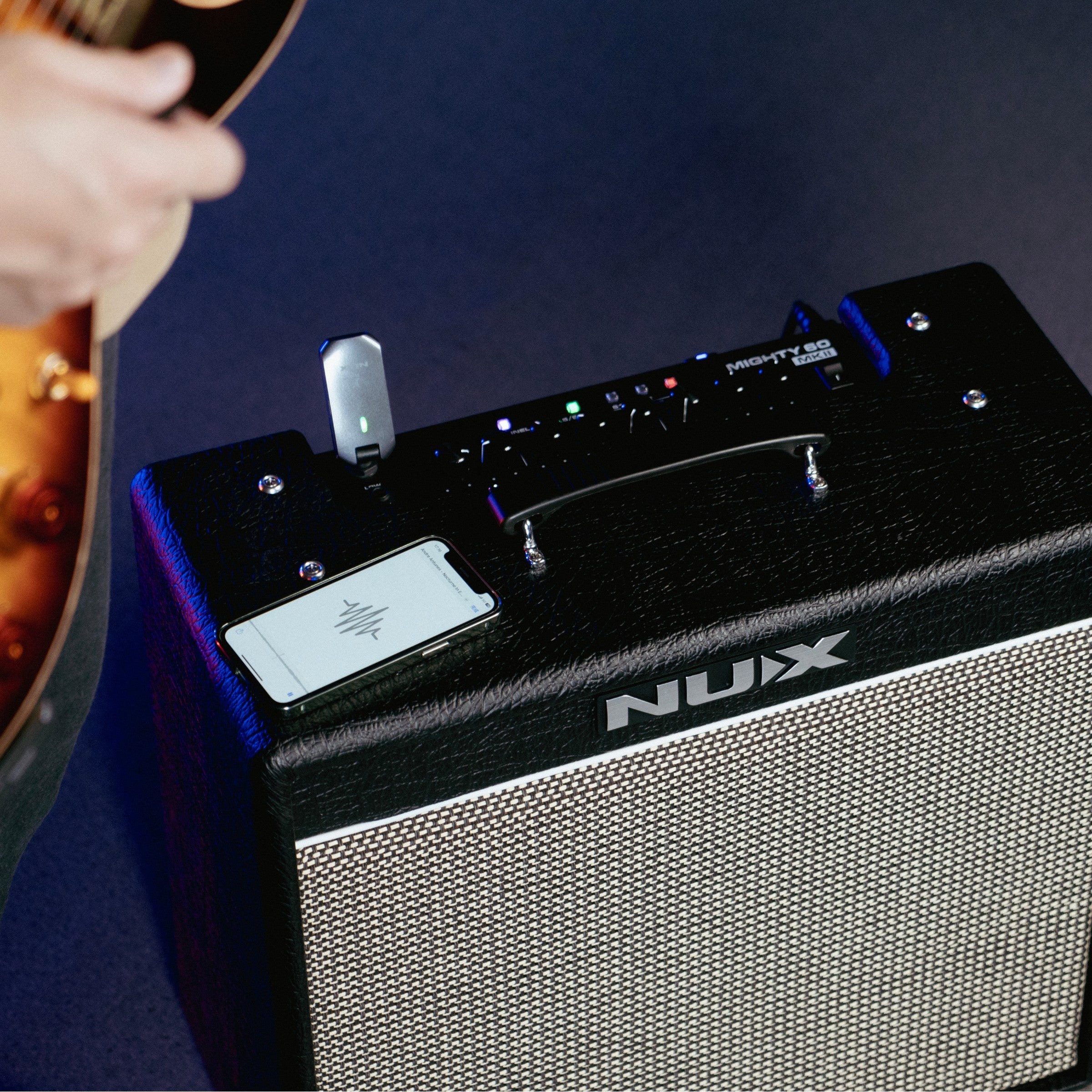Nux guitar amplifier with a person holding a guitar on a dark background