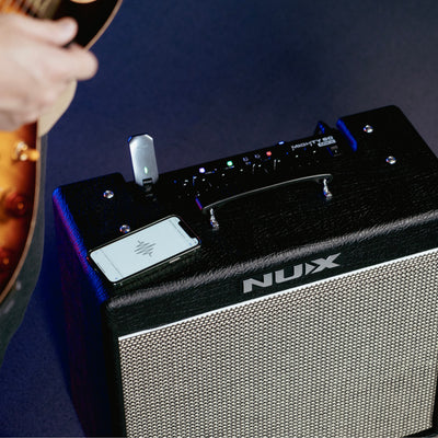 Nux guitar amplifier with a person holding a guitar on a dark background