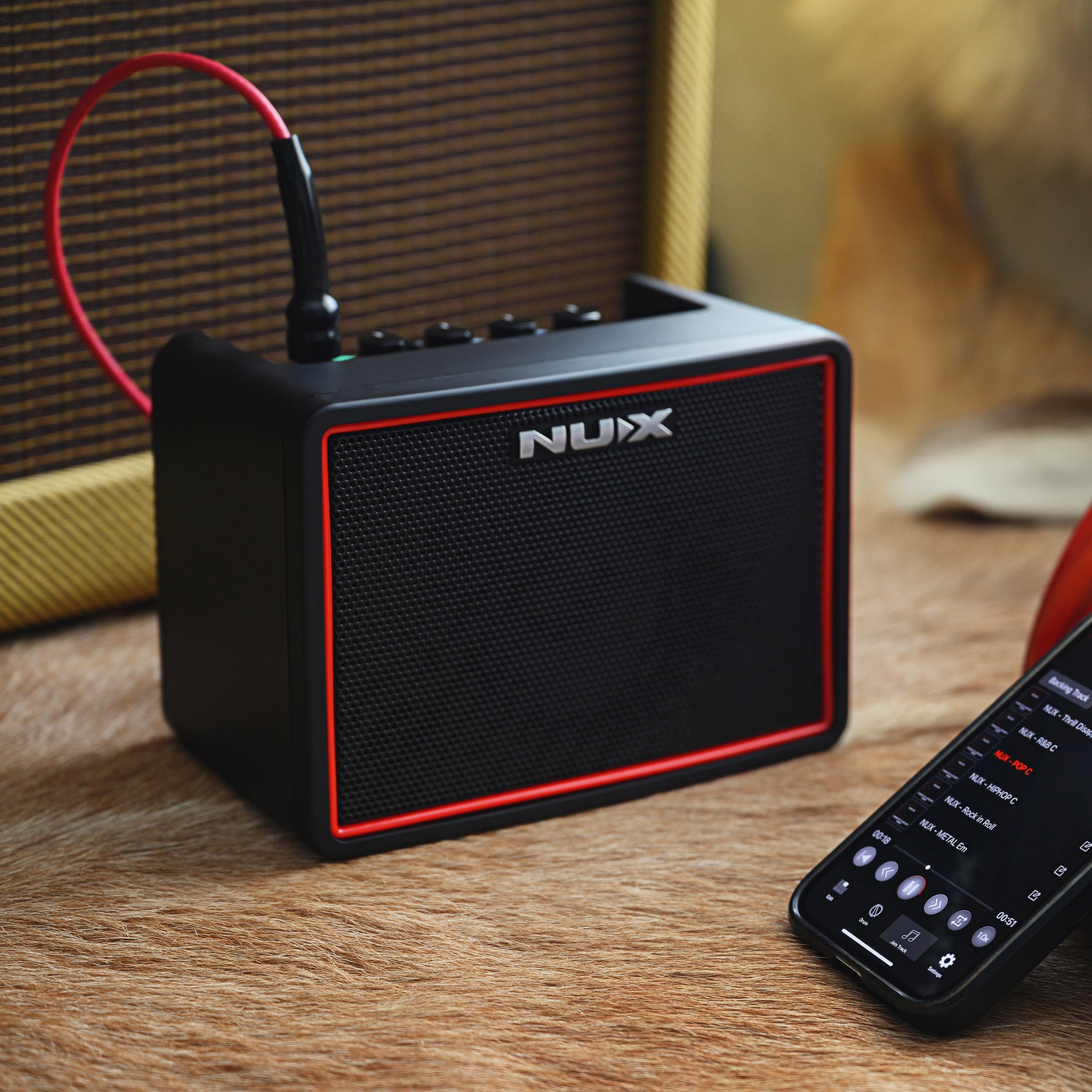 NUX amplifier on a wooden surface with a smartphone next to it