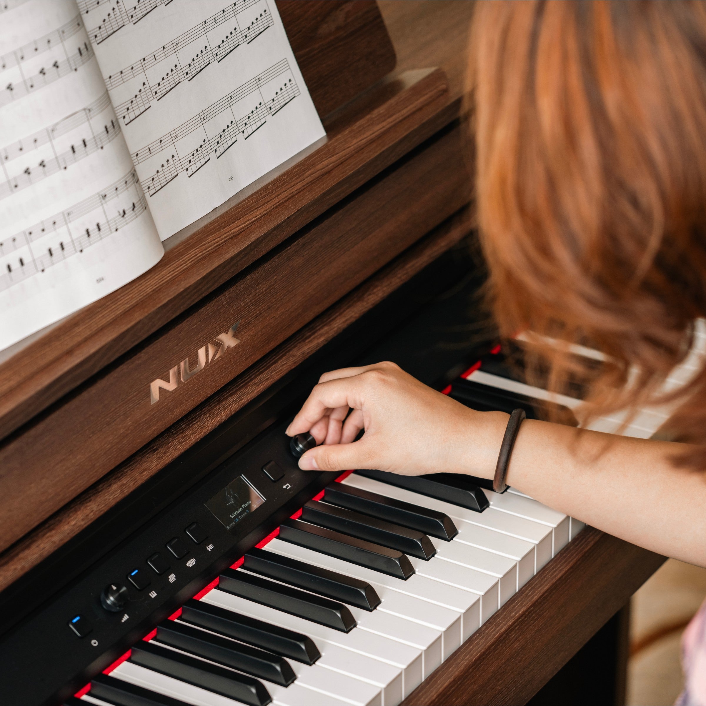 Person playing a NUX digital piano with sheet music in the background
