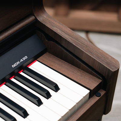 Close-up of a digital piano with wooden finish and NCK-430 branding.