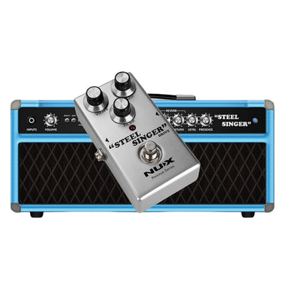 Guitar effects pedal labeled 'Steel Singer' by Nux in front of a blue and black amplifier.