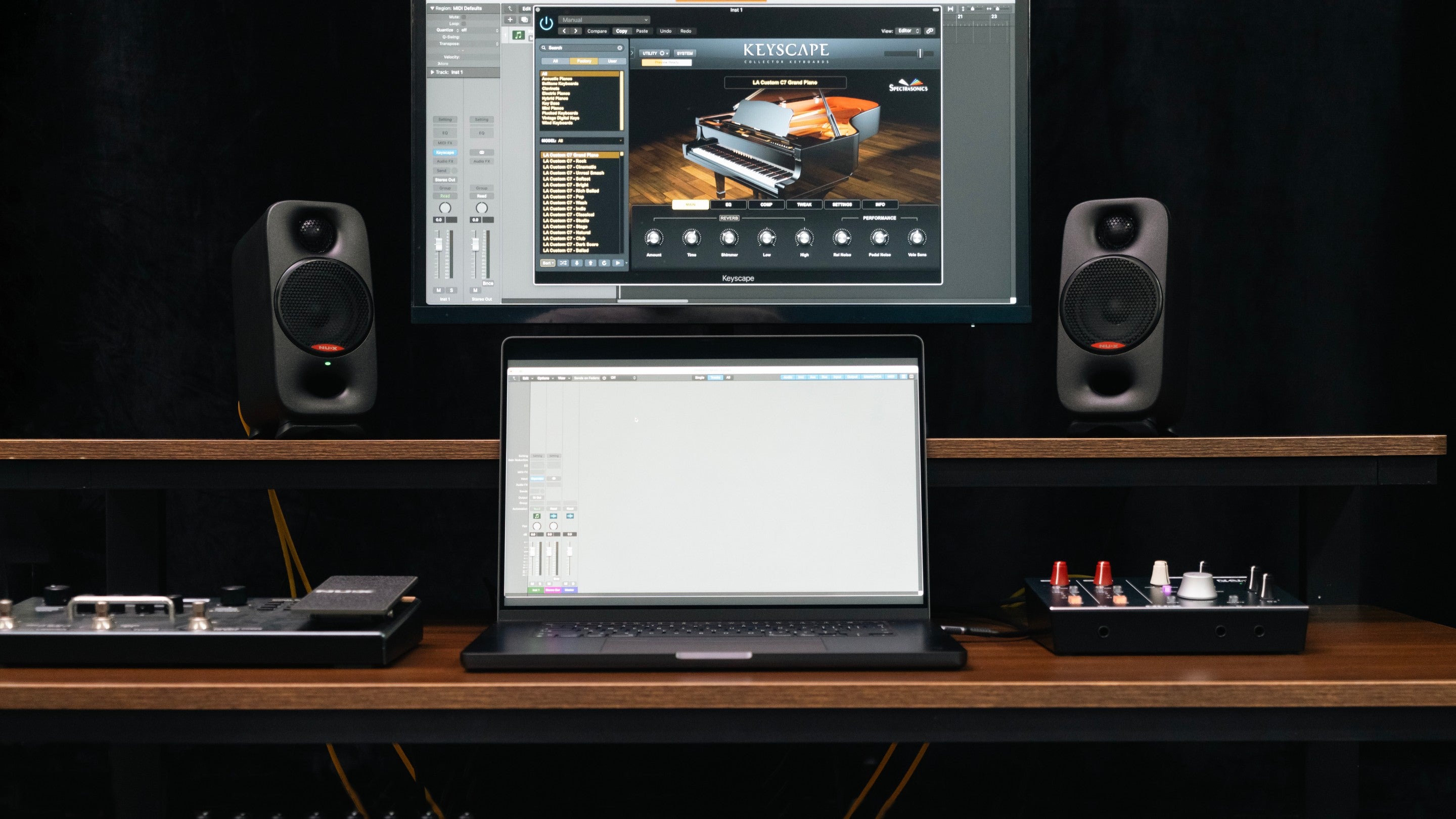 Music production setup with computer, nux monitor speakers, and music software on a dark background