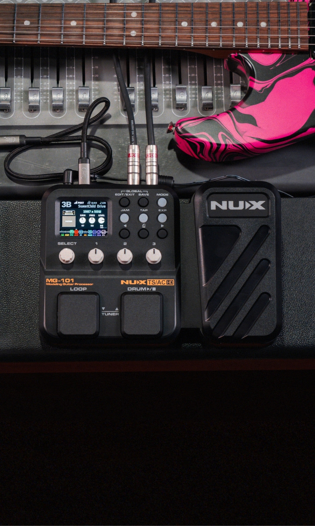 NUX MG-101 guitar effects pedal with laptop and pink electric guitar on a desk