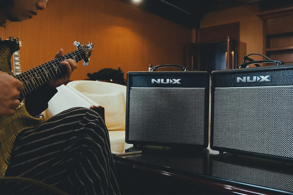 Person playing guitar with Nux amplifiers in a room setting
