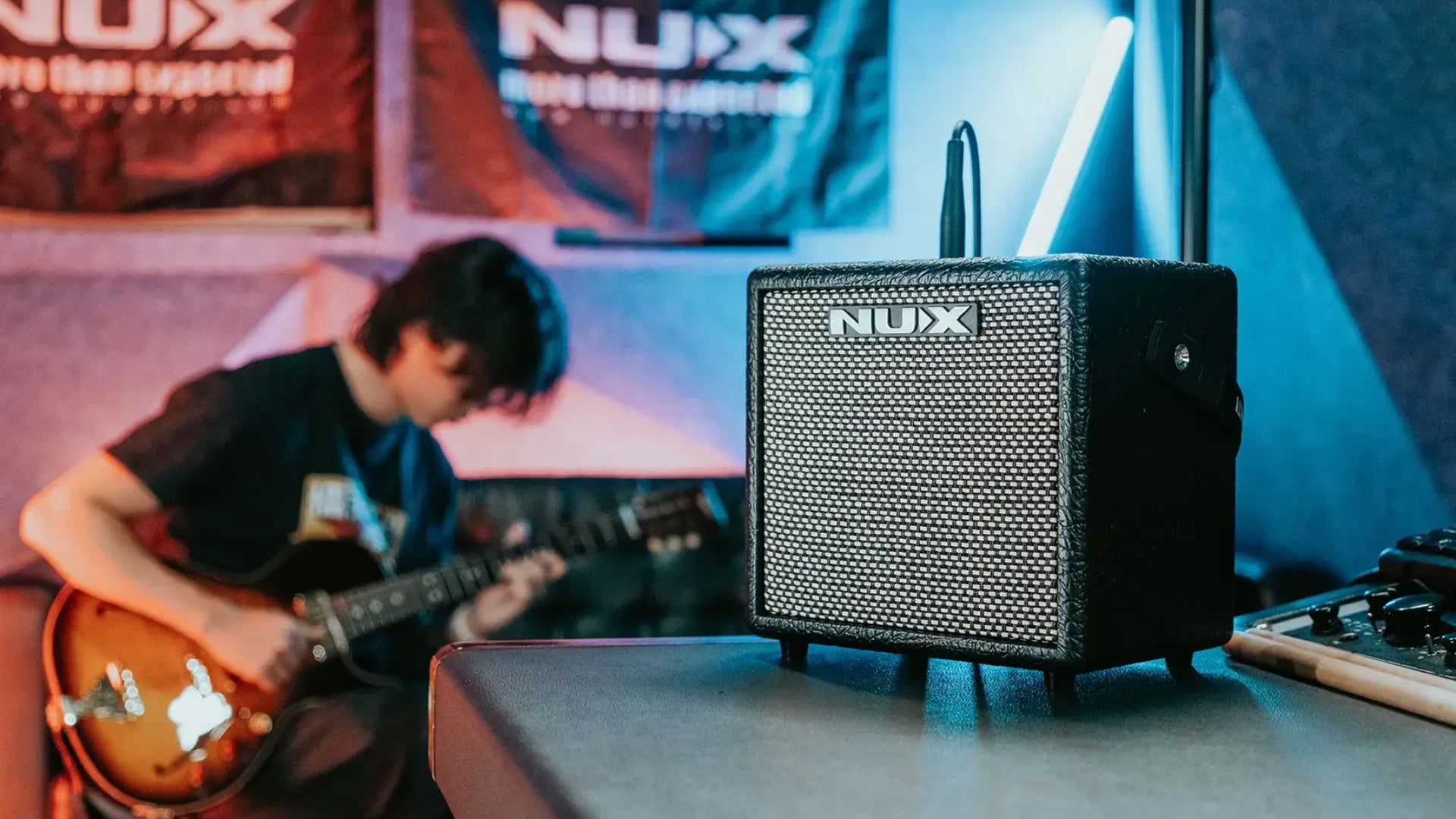 NUX mighty 8bt mkii small size amp in a studio with guitarist in the background playing