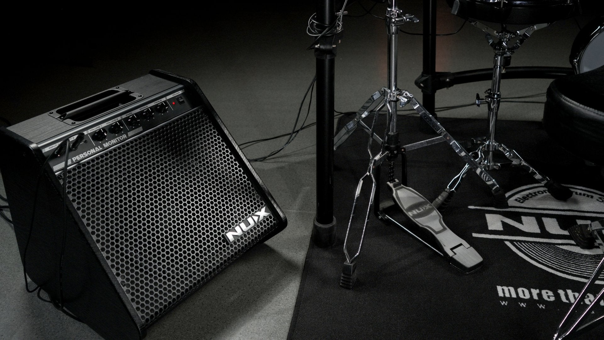 NUX personal monitor next to an electric drum kit on stage