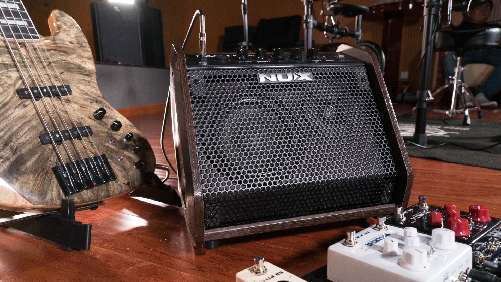 NUX PA-50 personal monitoring amplifier on a stage next to guitar and drum kit