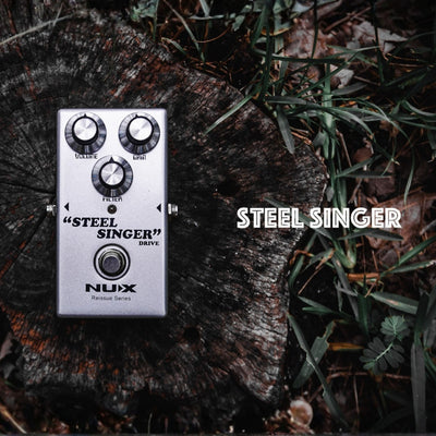 Nux Steel Singer guitar effects pedal on a wooden surface with grass.