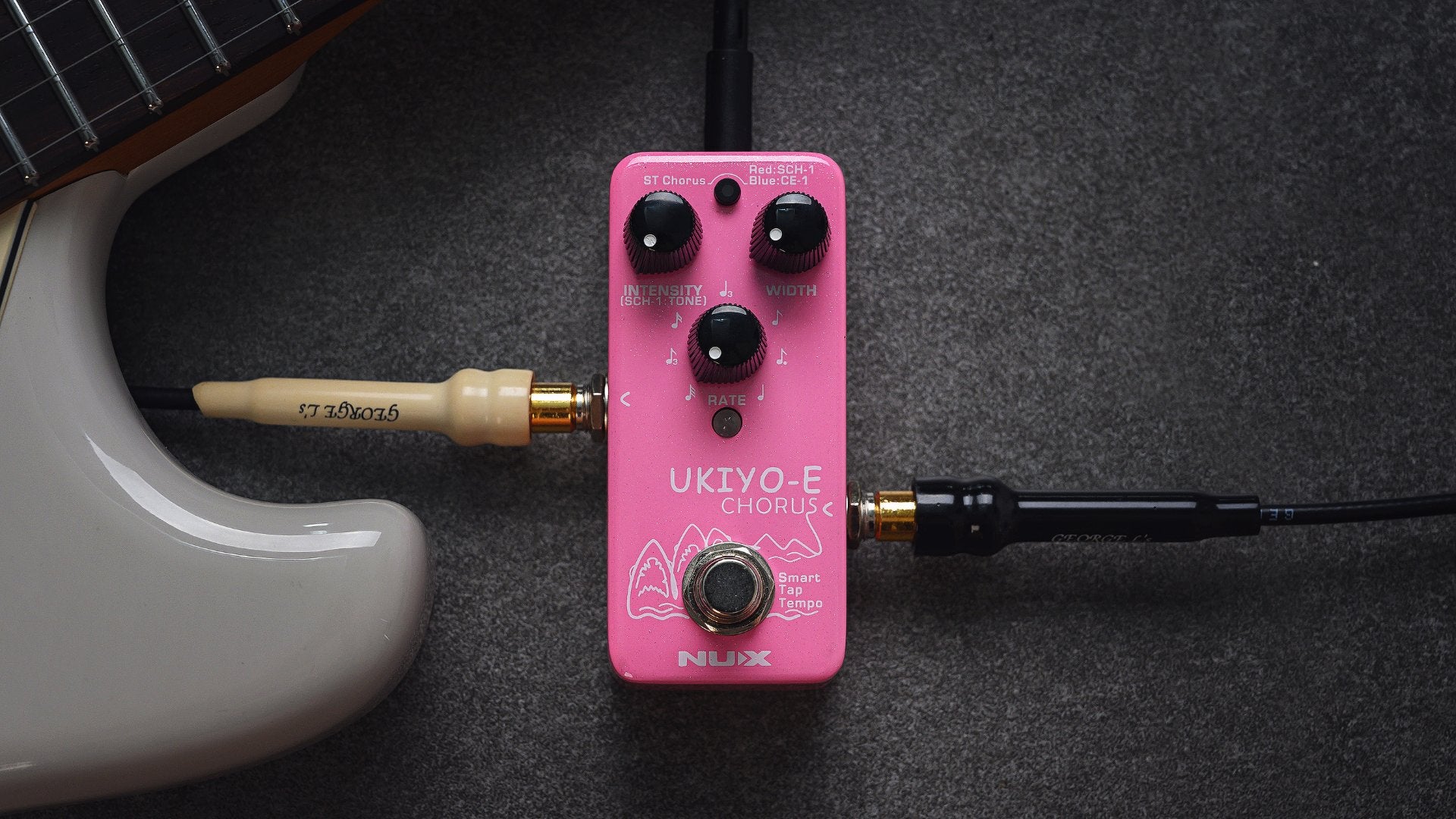 NUX Ukiyo-e chorus mini pedal on dark background next to a guitar